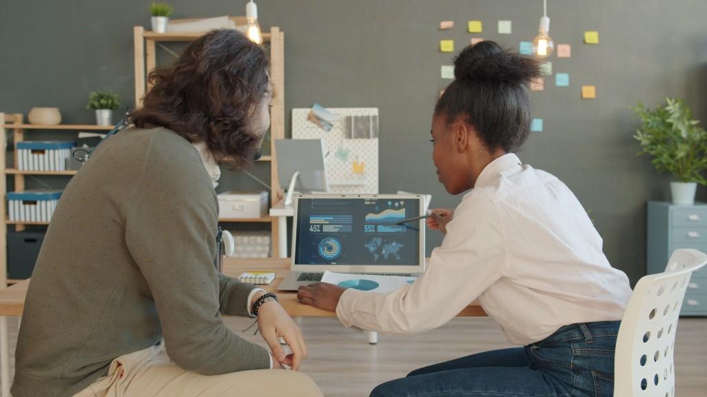 Two colleagues reviewing analytics dashboards on a laptop in a modern workspace